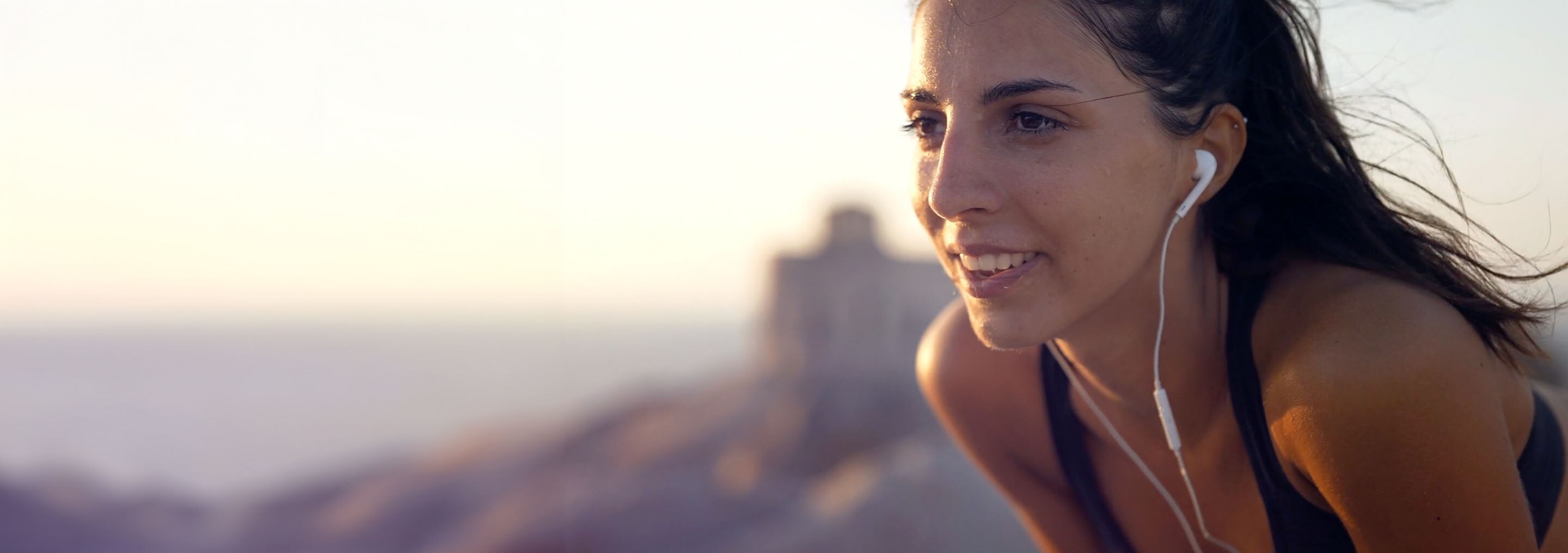 Mujer corriendo al aire libre con auriculares, disfrutando de un momento de ejercicio y bienestar.